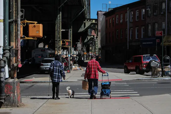 two seniors walking under an elevated subway track in Brooklyn
